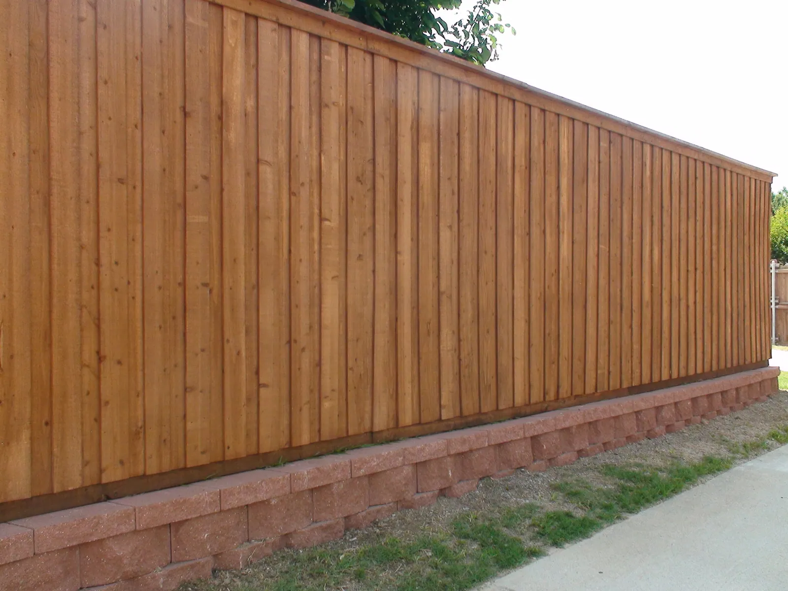 Red paver retaining wall board on board fence — Fence Max Texas project